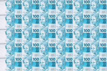 Background texture of Brazilian money bills, 100 reais notes, background for video or scenery. Concept of award or payment, fortune.