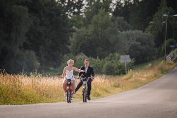 Fototapeta premium Couple riding bicycles on a scenic road, enjoying a sunny day, surrounded by lush greenery and wildflowers, capturing a moment of joy and connection in nature