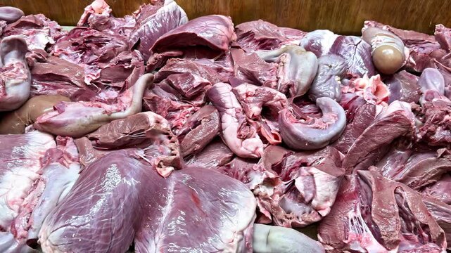 Pile of raw animal meat and internal organs spread on table for cleaning and preparation