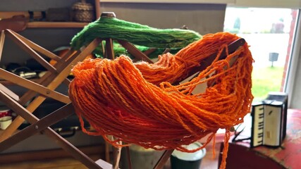 Bright orange and green wool yarn wrapped around a wooden yarn swift - Powered by Adobe