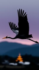 Black crane in flight over mountains &mdash; pale purple evening sky