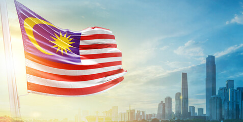 Malaysia flag wavering in beautiful clouds with building skyline. The flag with drone shot in beautiful sky. Malaysia national day flag for independence day.