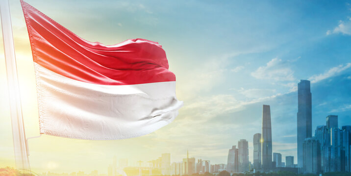 Monaco flag wavering in beautiful clouds with building skyline. The flag with drone shot in beautiful sky. Monaco national day flag for independence day.