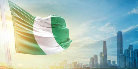 Nigeria flag wavering in beautiful clouds with building skyline. The flag with drone shot in beautiful sky. Nigeria national day flag for independence day.
