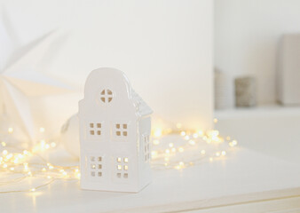 White ceramic house lantern with warm fairy lights and soft background