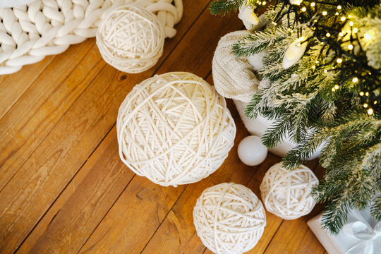 Warm yarn balls and Christmas tree lights on rustic wooden floor, cozy winter decor