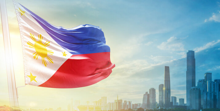 Philippines flag wavering in beautiful clouds with building skyline. The flag with drone shot in beautiful sky. Philippines national day flag for independence day.