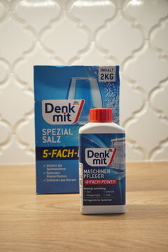 Dishwasher cleaner and salt products on a wooden surface with a tiled background