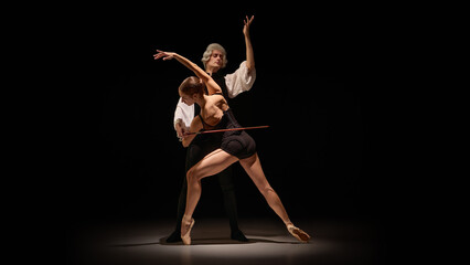 Dancer shaped into precise instrument-like line under mentor controlled guidance. Concept of flexibility training, movement shaping, performing arts instruction.