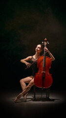 Ballerina seated on chair playing cello with poised theatrical grace. Concept of controlled artistry, stage identity, cultural storytelling, theatre materials, emotional communication for education.