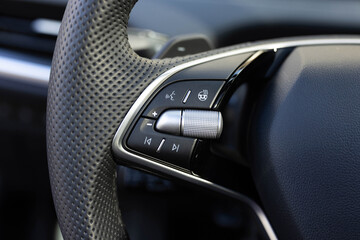 Heated steering wheel control buttons with blurred dashboard in car interior. Steering wheel heating control panel. Volume button of car radio on steering wheel. Turns up the volume of the music.