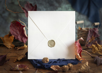 Envelope on wood near autumn dried leaves closeup, wedding and party, rustic mockup
