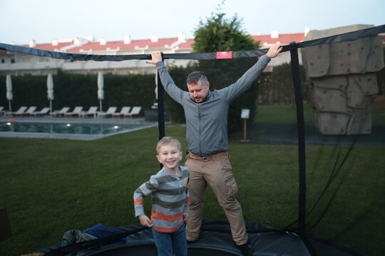 Father and son playing together on backyard trampoline - Powered by Adobe