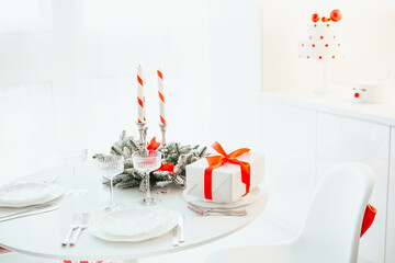 Festive table setting with gift box, candles, and elegant glasses on a white surface