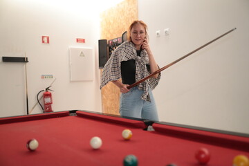Woman playing pool holding billiard cue thinking strategy