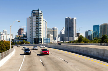 Highway to North Miami with cars driving, modern skyscrapers rising behind under a bright blue sky.