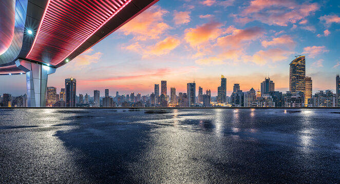 Empty wet asphalt road and modern city commercial buildings with skyline at sunset in Shanghai