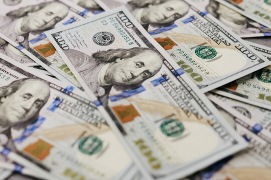 Close-up view of multiple hundred dollar bills stacked together, showcasing intricate details of currency design and vibrant colors, representing wealth and financial transactions - Powered by Adobe