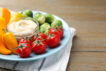 Different fresh vegetables and sauce on wooden table, closeup. Space for text
