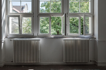 An interior perspective of a row of modern white-framed windows, several of which are tilted open...