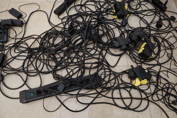Chaotic mess of tangled electrical extension cords and power strips