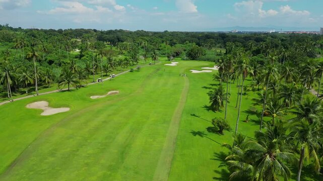 An aerial view showing fairways, water puddles, tropical trees, and a paved path with golf carts in Canlubang Golf and Country Club, Calamba Laguna, Philippines