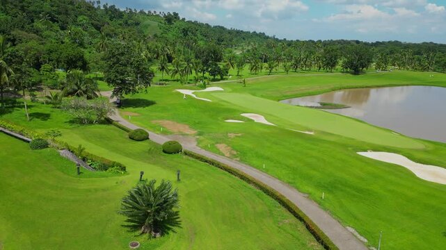 An elevated aerial passing over tropical trees, revealing fairways, water features, and the clubhouse of Canlubang Golf and Country Club in Calamba Laguna, Philippines