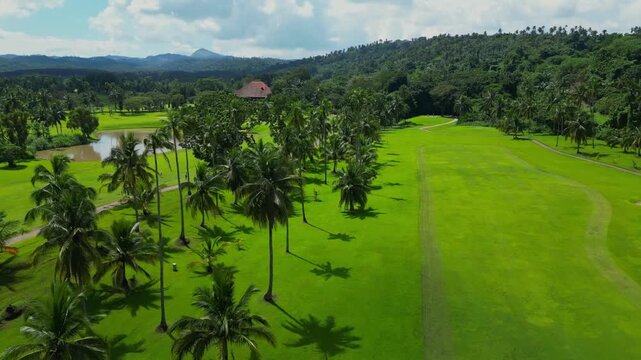 A rising aerial from the fairways toward the huge water puddle beside tropical trees in Canlubang Golf and Country Club, Calamba Laguna, Philippines