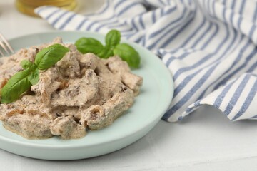 Tasty beef Stroganoff with basil on white table, closeup. Space for text