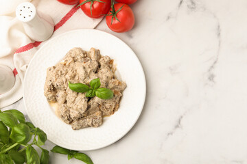 Tasty beef Stroganoff with basil and tomatoes on white marble table, flat lay. Space for text