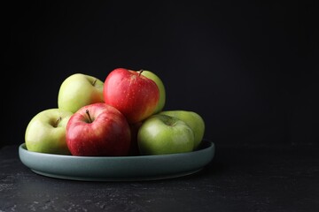 Fresh red and green apples on dark textured table against black background, closeup. Space for text