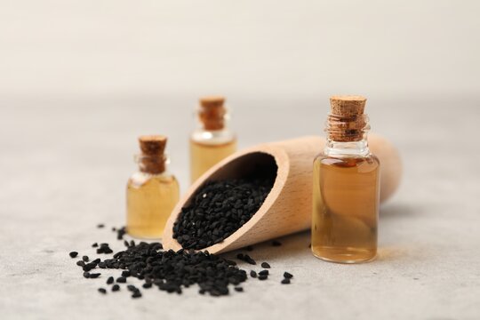 Black cumin seeds and oil on light grey table, closeup