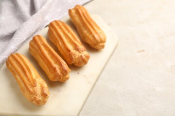 Fresh tasty eclairs on light table, closeup. Space for text