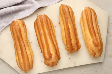 Fresh tasty eclairs on light table, top view