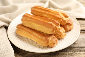 Fresh tasty eclairs on wooden table, closeup