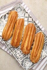 Fresh tasty eclairs on light table, top view