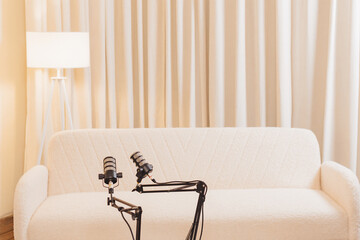 Podcast setup with microphones and cozy seating in modern studio space
