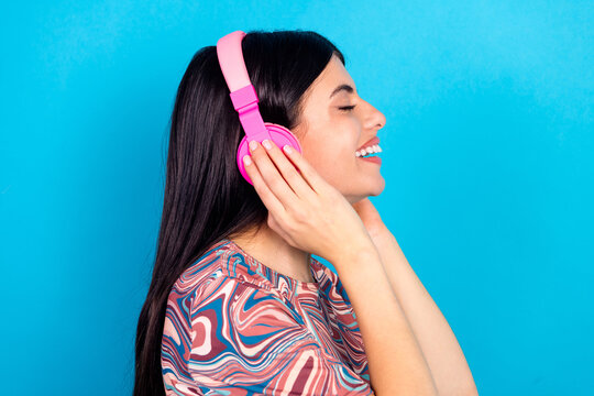 Girl enjoying music with pink headphones smiling blue background in casual printed top youthful fashion lifestyle for advertising  branding