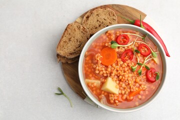 Delicious lentil soup with vegetables served on light grey table, top view. Space for text