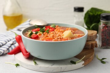 Delicious lentil soup with vegetables served on light grey table, closeup