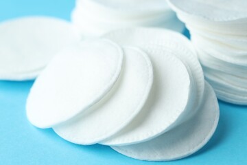 Clean cotton pads on light blue background, closeup