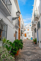 Narrow street of Frigiliana, Malaga, Andalusia, Spain. Cozy Andalusian town with white houses, flowers, colorful doors and windows. White Village. Travel concept