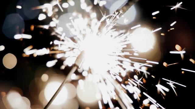 Sparklers are burning in people's hands and sparks are flying in different directions
