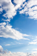 Obraz premium clear blue sky with white fluffy clouds. vertical nature background. soft cumulus cloudscape wallpaper on a bright day. fresh air due to reduced emission in summer atmosphere