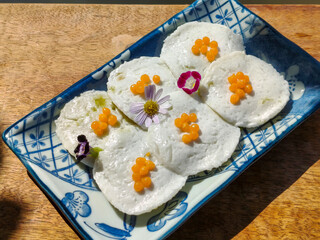 Close up view of Steamed Coconut Custard or Kanom Tuay. Thai dessert made from rice flour, coconut milk and sugar steamed in small ceramic cups with pandan leaves and coconut milk poured over it
