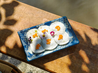 Steamed Coconut Custard or Kanom Tuay. Thai dessert made from rice flour, coconut milk and sugar steamed in small ceramic cups with pandan leaves and coconut milk poured over it. Top view