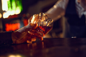 Close-up hands clinking whiskey glasses in dim bar. Concept of drink specials, premium alcohol branding, bar menu hero shots, nightlife advertising, and social toast visuals.
