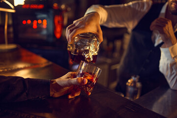 Bartender pouring whiskey from bottle into glass. Concept of professional bar service, mixology...
