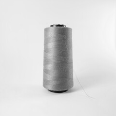Grey thread spool standing on clean white background