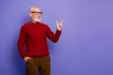 Mature man in red sweater points with smile against violet background for lifestyle advertising and fashion